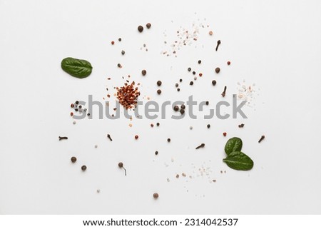 Different spices and spinach leaves on light background