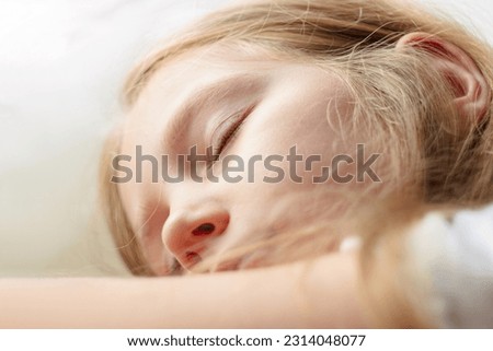 Calm blond child girl sleeps on white soft pillow in comfortable cozy bed Kids closed eyes portrait skin close-up. Sleeping app Deep sleep-tracking sonar technology smartphone monitoring Mental health