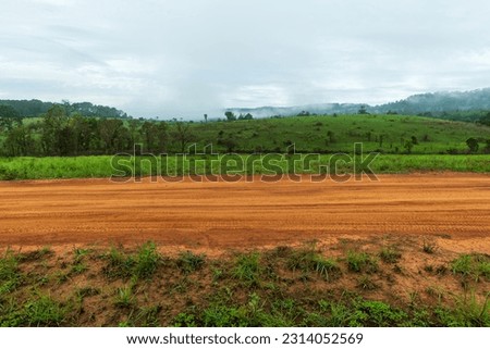 Side view of gravel road in countryside with meadow Royalty-Free Stock Photo #2314052569