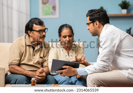 Indian doctor explaining from digital tablet to senior couple about medical report at home - concept of technology, health care support and home consultation. Royalty-Free Stock Photo #2314065539