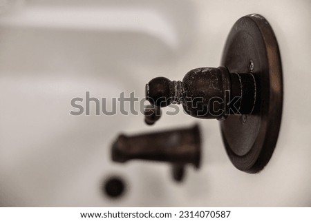 An oil rubbed bronze shower handle that needs to be cleaned from a white buildup of dirt, calcium, mineral deposits and hard water. Royalty-Free Stock Photo #2314070587