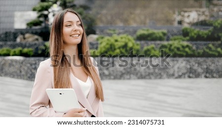 Happy caucasian business woman in a beige business suit smiling holding a tablet in her hands and looking away. Internet marketer. web banner. copy space
