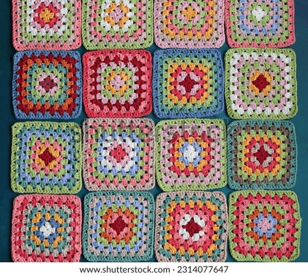 Handmade crocheting with colorful threads and scissors on textured background. 