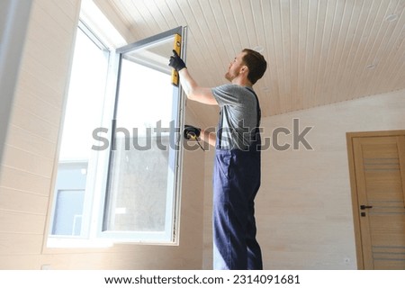 Construction worker installing new window in house. Royalty-Free Stock Photo #2314091681