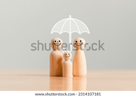 Happy family under the umbrella on raining wooden figurine model on table top background. People lifestyles and Relationships in love concept.