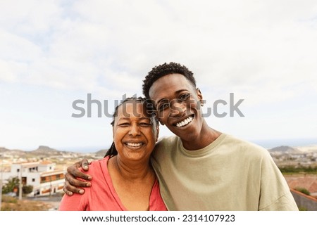 Happy African grandson hugging her grandmother at house rooftop Royalty-Free Stock Photo #2314107923