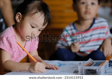 Little asian girl was coloring cartoons on coloring book at home. Coloring Book Education Talent Concept. Copy space.