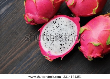 Fresh Ripe Dragon Fruit Cut in Half with Heap of Whole Fruits on Wooden Background