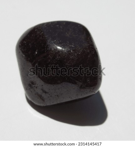 A close-up of a polished garnet stone, shimmering with its deep red hues. Royalty-Free Stock Photo #2314145417