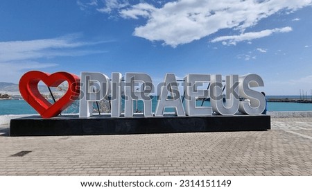 The touristic sign with the name of Piraeus city in the port under a blue sky in Greece