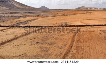 A wide desert field with canyons and mountain