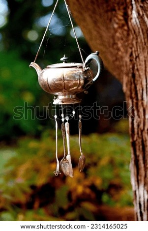 A vertical closeup shot of a metal decorative garden wind chimes hung on a tree Royalty-Free Stock Photo #2314165025