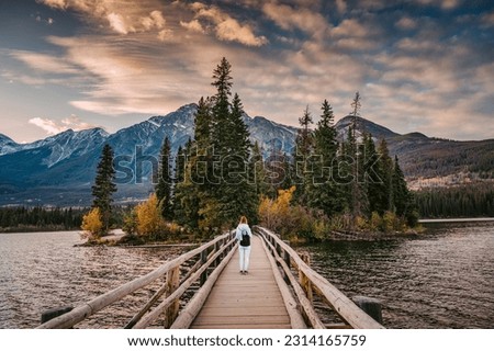 Female tourist standing on wooden bridge and tiny island on Pyramid Lake in the evening at Jasper national park, AB, Canada Royalty-Free Stock Photo #2314165759