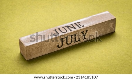 June and July text on grunge wooden block against handmade green rag paper, calendar concept