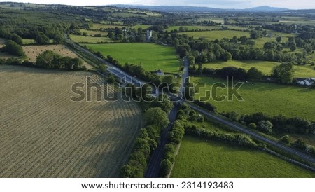 A drone shot of a road between fields and  Jerpoint Abbey Ruins in Thomastown, county Kilkenny