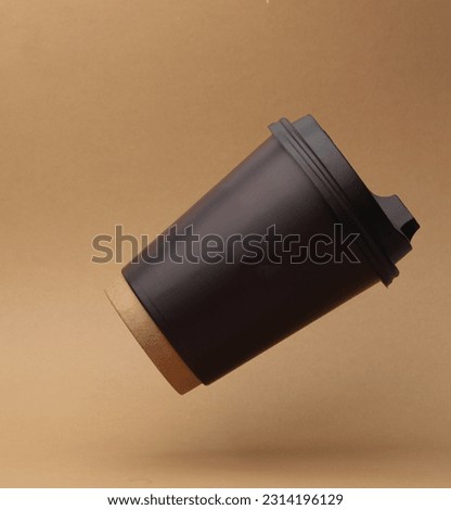 Brown Disposable take out cup for hot drinks (tea, coffee) levitating on beige background with shadow