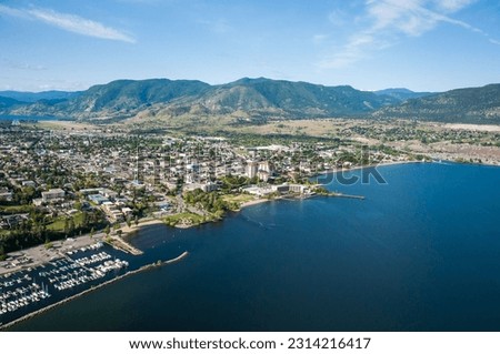 An aerial shot of the Okanagan Lake with Penticton city on the shore and hills in the background
