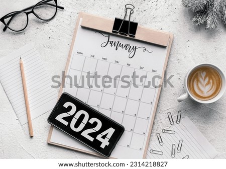 Top view of clipboard with January 2024 calendar on table. Number 2024 on mobile phone screen. Royalty-Free Stock Photo #2314218827