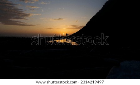 This picture was taken of a beautiful sunset at Cooski Campground in Northern California Lost Coast Trail.  You see a couple enjoying the marvelous sunset.  Their silhouette reflecting off the water.