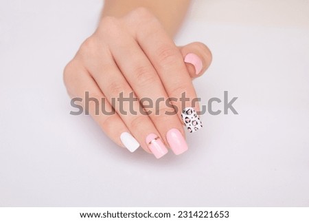 
Beautiful female hand with pink manicure nails, leopard print design on white background
