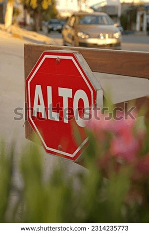 A vertical shot of a red wooden stop sign in Spanish in Mexico