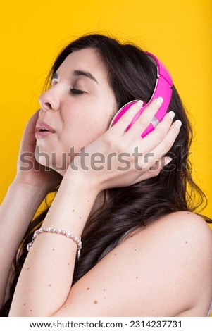 Young woman, wearing pink headphones, savours the engulfing sounds of music, storytelling, on a colorful background