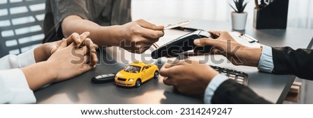 Customer client purchases new car with credit card via electronic terminal after finishing the deal with car dealer. Smooth car ownership transfer with secure electronic digital payment. Prodigy