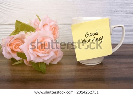 Pink rose and adhesive paper note on coffee mug with text - Good morning
