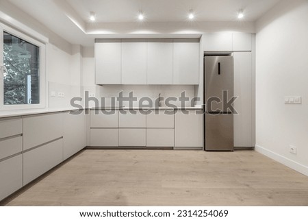 Modern L-shaped kitchen with handleless cabinets, white stone countertops and integrated appliances