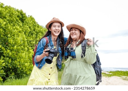 Two Asian women holding a camera sea ​​tourism Travel concept, nature tourism. Asian tourists