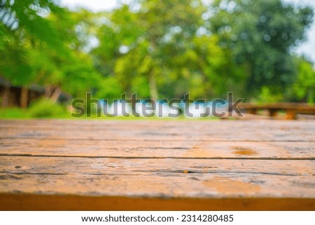 Selected focus empty wooden table and view of green forest blur background with bokeh image. for your photo montage or product. Empty brown wooden table and blur background of camping