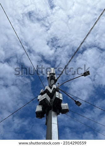 Cellular communication equipment on a lamppost against a cloudy sky