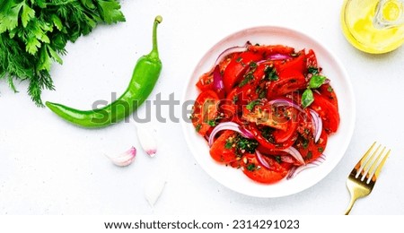Tomato and onion salad with parsley, garlic, jalapeno and olive oil dressing, white table background, top view