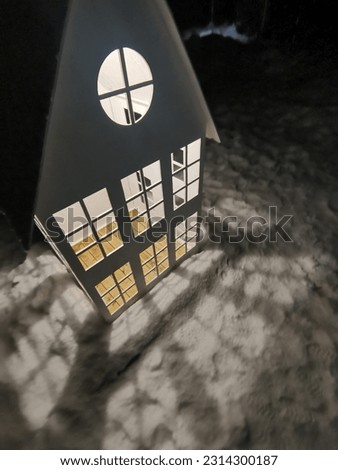 Dollhouse with light from windows on a winter street
