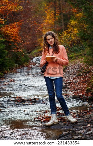 Young artist with sketch in note at autumn landscape