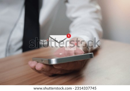 businessman holding a phone along with the e-mail icon. New email notification ideas for business email communication and digital marketing. The inbox receives electronic message notifications.