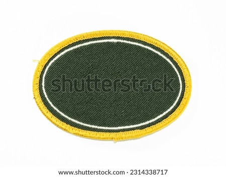 Dark green oval patch with white inner trim and gold outer trim.