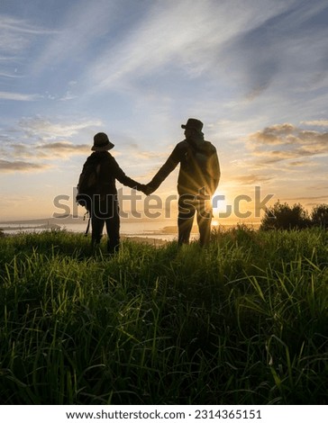 Couple standing on Mt Eden summit and looking at Rangitoto Island at sunrise. Auckland. Vertical format.    Royalty-Free Stock Photo #2314365151