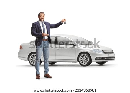 Young professional man holding a car key in front of a sliver car isolated on white background
