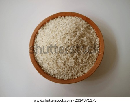 White rice in wooden bowl on white background. Close up, top view, high resolution product.
