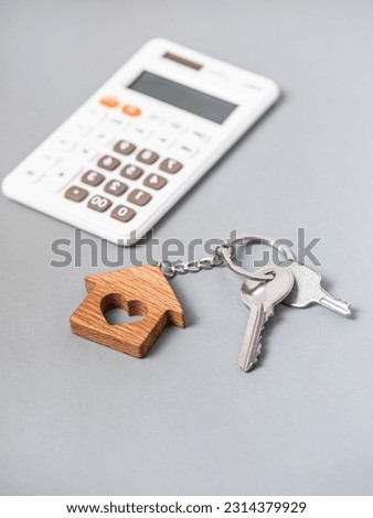 Keys to a new house. Calculator. Gray background. Buying a property. Credit. Mortgage. Vertical photo.