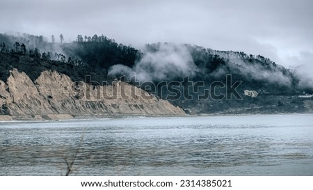 cliffs and hills at the coast covered with clouds.