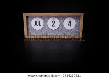 A wooden calendar block showing the date July 24th on a dark black background, save the date or date of event concept