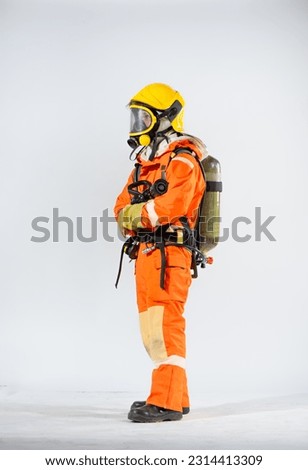 Side view of firefighter wearing yellow hard hat standing holding fire hose with both hands on white background.
