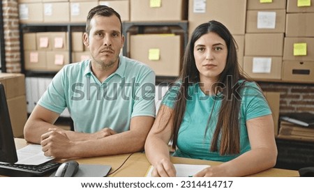 Two coworkers working looking a the camera at ecommerce office