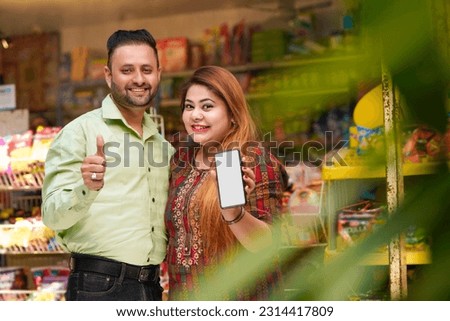 Indian couple showing smartphone screen at grocery shop.