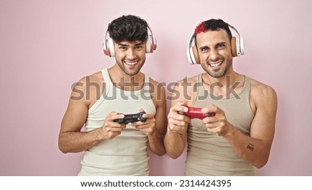Two men smiling confident playing video game over isolated pink background
