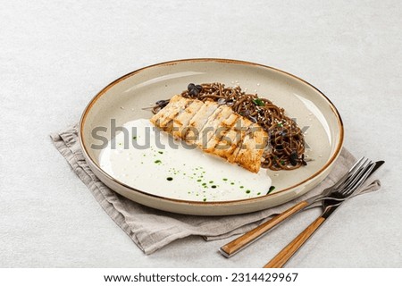 Portion of halibut fillet with soba noodles and creamy sauce