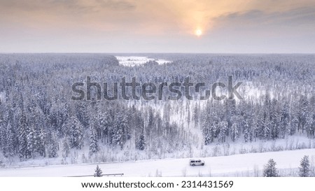 A cross-country vehicle moves along a snowy winter road in the Russian north.