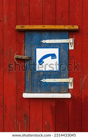 Wooden cabinet with red and blue doors and phone symbol sign.